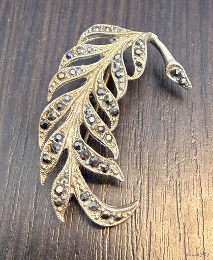 Винтажная брошь, выполненная в форме изящного пера.